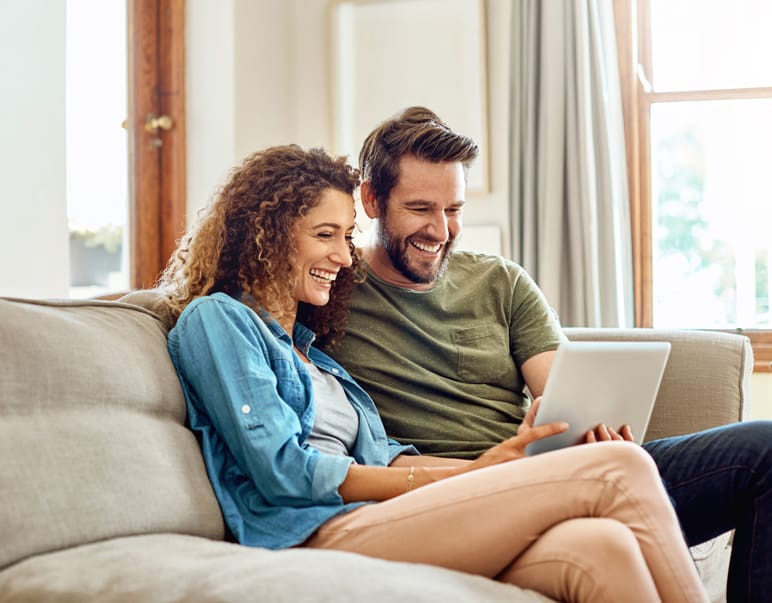 Cool Smiles Orthodontics - Couple sitting on couch smiling at ipad